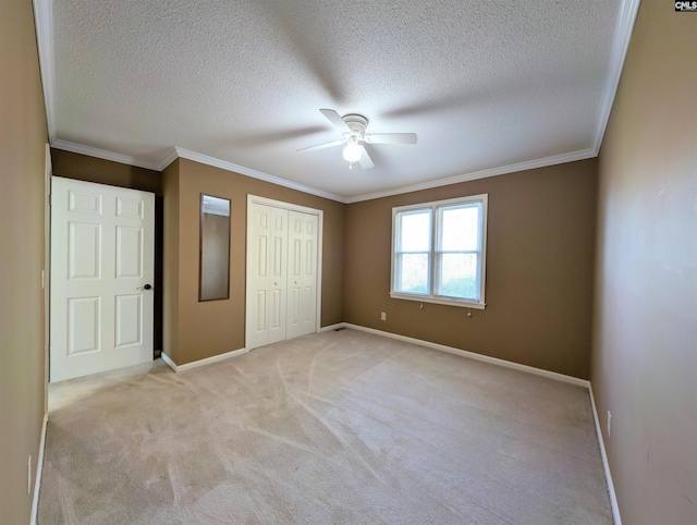 unfurnished bedroom featuring a textured ceiling, ceiling fan, ornamental molding, and light carpet