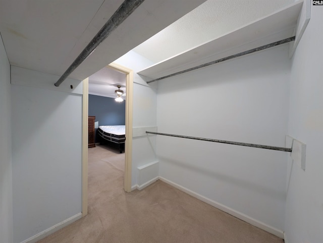 spacious closet with light colored carpet and ceiling fan