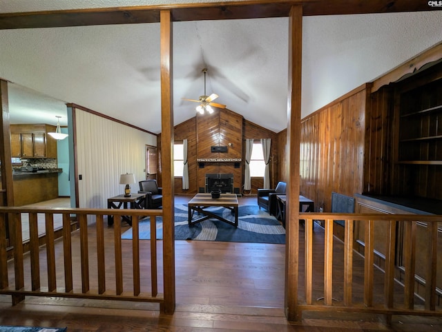 living room with hardwood / wood-style flooring, vaulted ceiling, ceiling fan, and wood walls