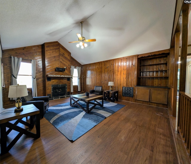 living room with wooden walls, plenty of natural light, hardwood / wood-style floors, and vaulted ceiling