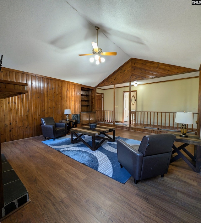 living room featuring a textured ceiling, ceiling fan, wood-type flooring, lofted ceiling, and wood walls