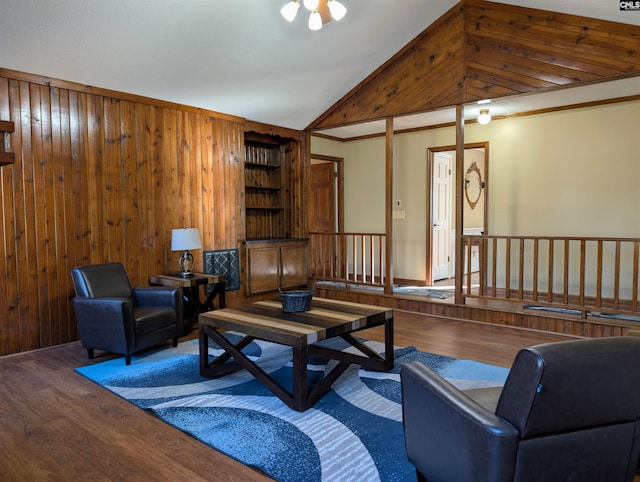 living room featuring hardwood / wood-style floors, wood walls, lofted ceiling, and crown molding