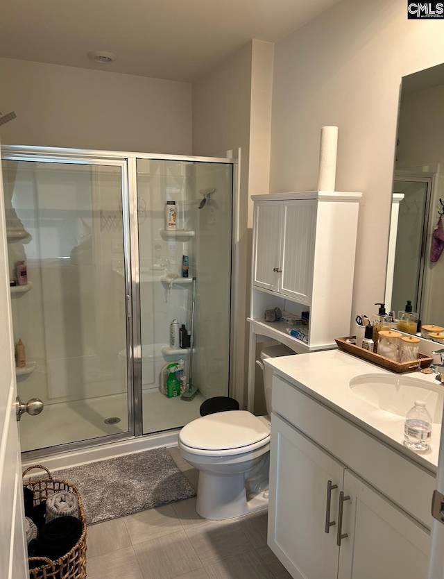 bathroom featuring tile patterned floors, vanity, an enclosed shower, and toilet