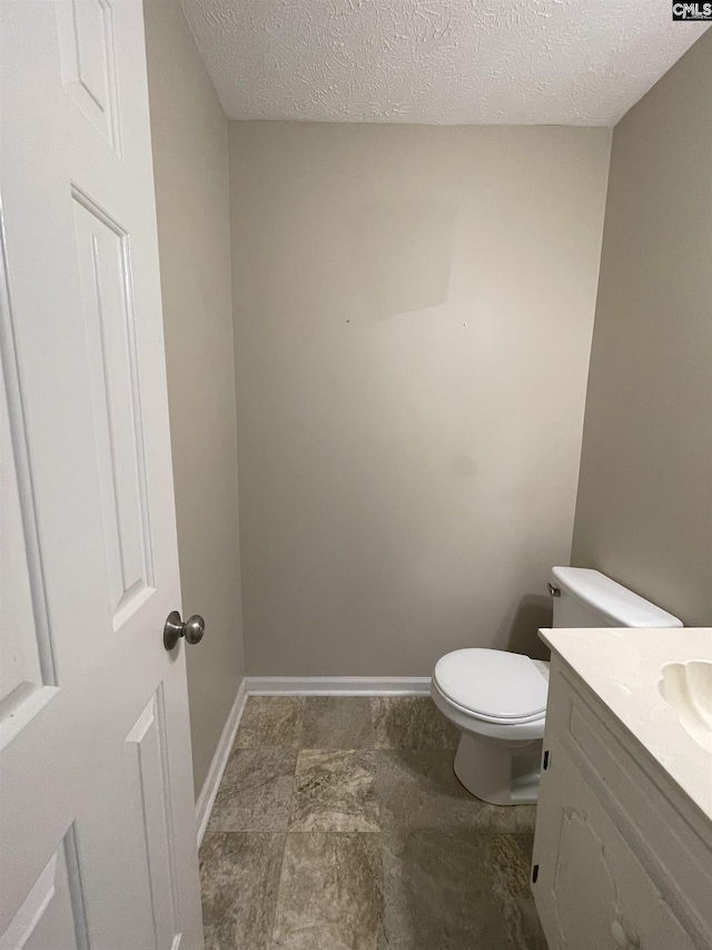 bathroom featuring vanity, toilet, and a textured ceiling