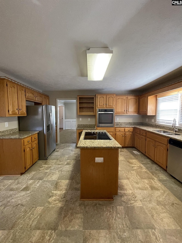 kitchen featuring a center island, stainless steel appliances, a textured ceiling, and sink