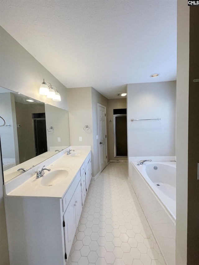 bathroom featuring vanity, plus walk in shower, and a textured ceiling