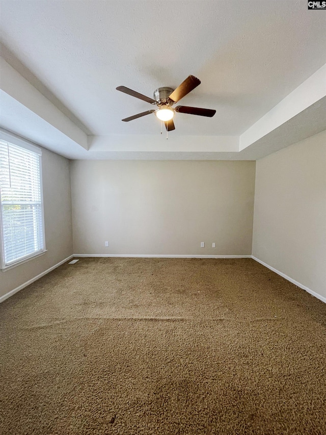 carpeted spare room with a tray ceiling and ceiling fan