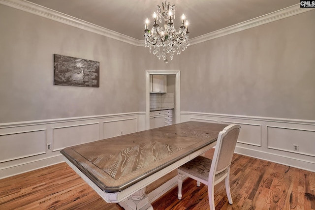 dining room with wood-type flooring, crown molding, and an inviting chandelier