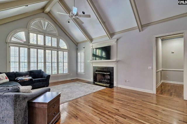 unfurnished living room featuring high vaulted ceiling, light hardwood / wood-style flooring, ceiling fan, a fireplace, and beamed ceiling