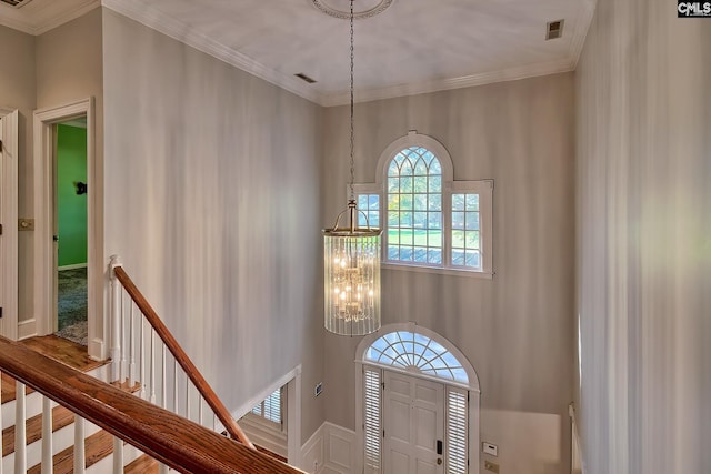 entrance foyer with crown molding, a chandelier, and hardwood / wood-style flooring