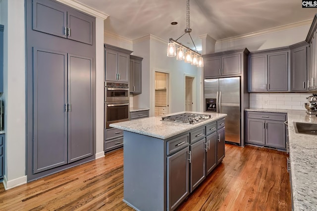 kitchen featuring tasteful backsplash, crown molding, wood-type flooring, decorative light fixtures, and appliances with stainless steel finishes