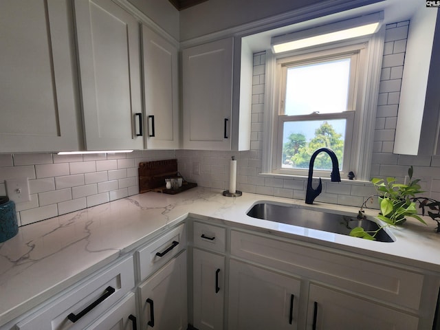 kitchen with decorative backsplash, white cabinetry, and sink