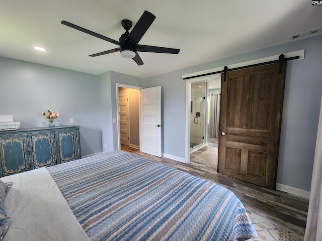 bedroom featuring ceiling fan, a barn door, dark wood-type flooring, and connected bathroom