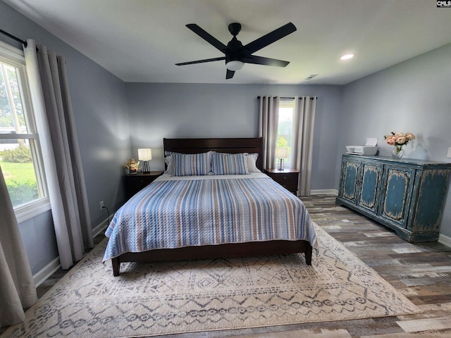 bedroom with hardwood / wood-style flooring, multiple windows, and ceiling fan