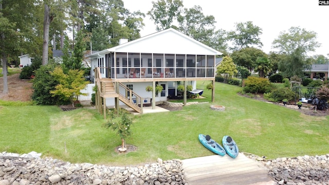 back of house featuring a sunroom, a yard, and a fire pit