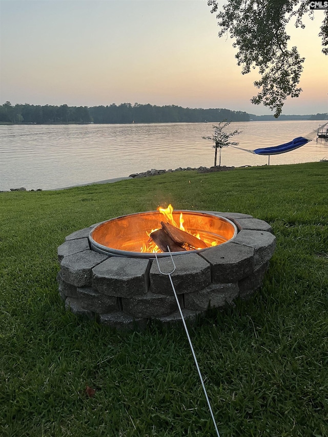 yard at dusk featuring a fire pit and a water view