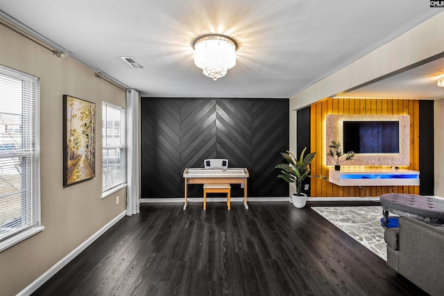 home office with dark hardwood / wood-style floors, an inviting chandelier, a wealth of natural light, and wood walls