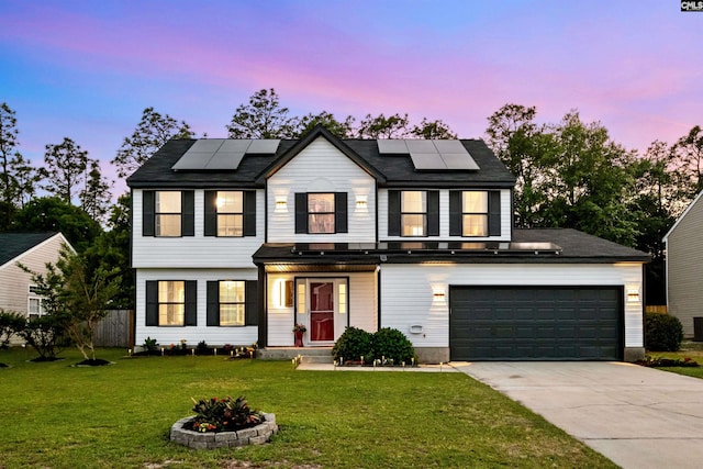 view of front of property featuring solar panels, a garage, and a lawn