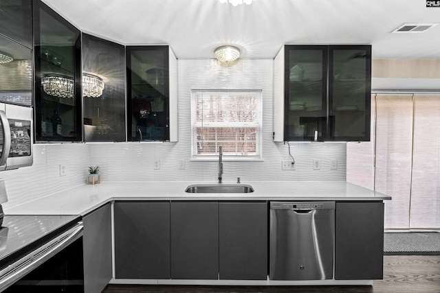 kitchen with sink, stainless steel appliances, an inviting chandelier, backsplash, and light hardwood / wood-style floors