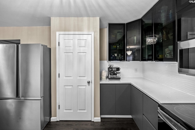 kitchen with a notable chandelier, dark hardwood / wood-style flooring, appliances with stainless steel finishes, and tasteful backsplash