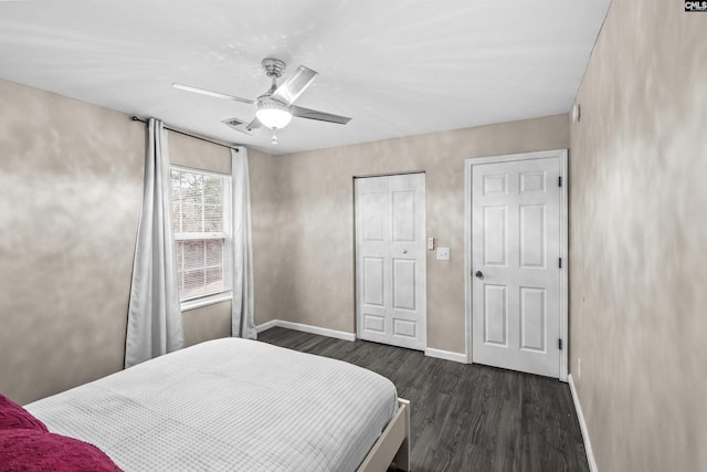 bedroom featuring ceiling fan, dark wood-type flooring, and two closets