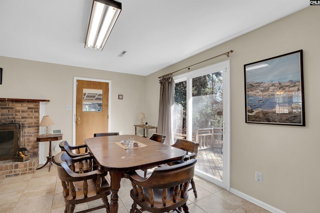 dining space with light tile patterned flooring and a brick fireplace