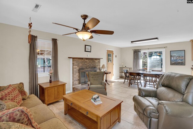 living room with light tile patterned floors, a brick fireplace, and ceiling fan