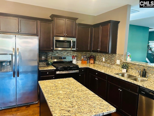 kitchen with sink, stainless steel appliances, light stone counters, dark hardwood / wood-style floors, and backsplash