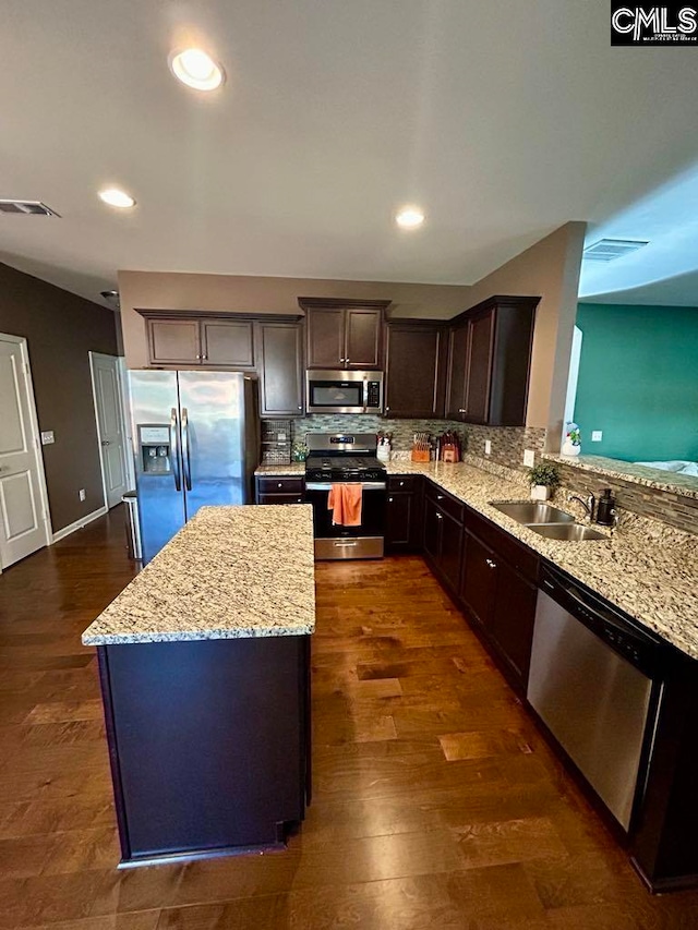 kitchen featuring light stone countertops, dark hardwood / wood-style flooring, dark brown cabinetry, stainless steel appliances, and sink