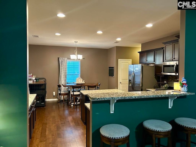 kitchen featuring a kitchen bar, appliances with stainless steel finishes, tasteful backsplash, and dark brown cabinets