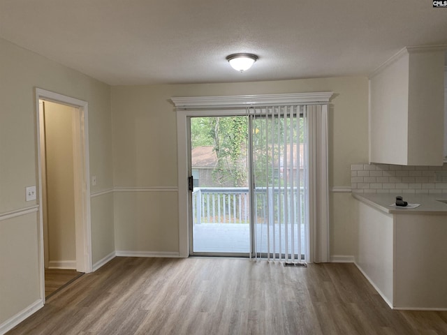 unfurnished dining area featuring hardwood / wood-style flooring and a textured ceiling