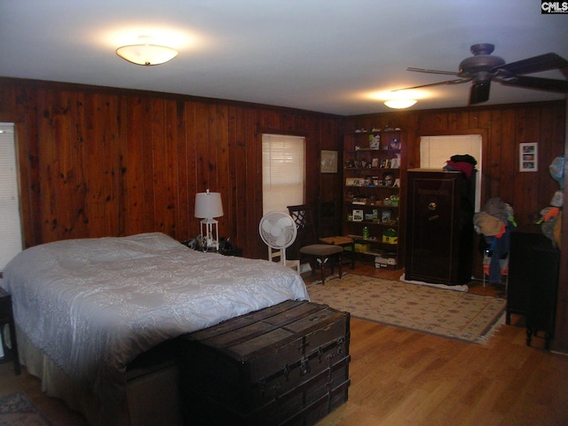 bedroom with hardwood / wood-style flooring, ceiling fan, and wooden walls