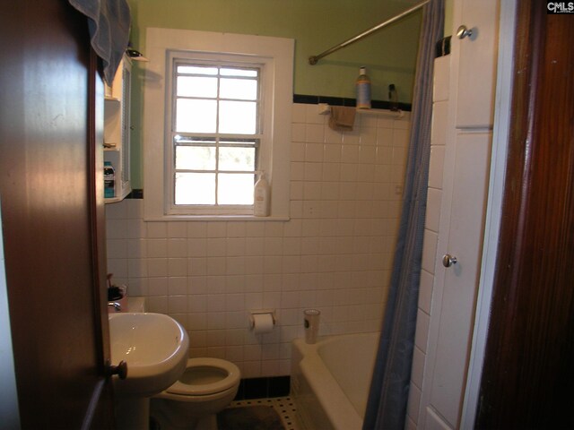 bathroom featuring tile patterned flooring, toilet, and tile walls