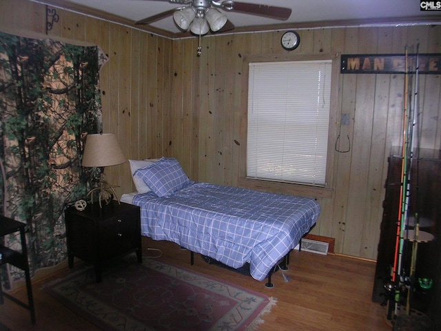 bedroom with hardwood / wood-style flooring, ceiling fan, and wooden walls