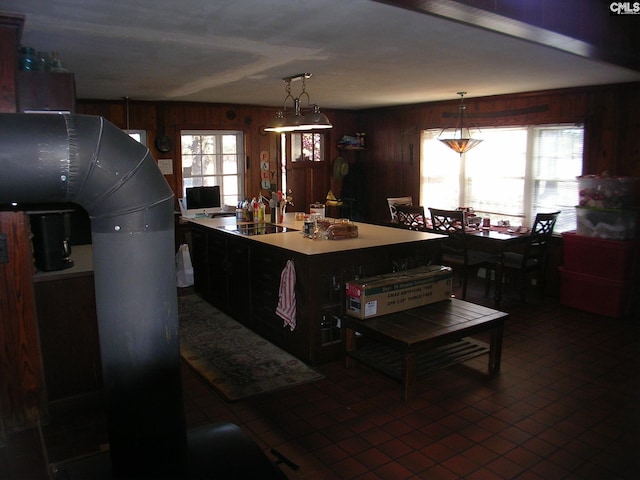 kitchen featuring tile patterned floors, wood walls, black electric stovetop, and decorative light fixtures