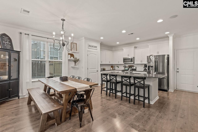 dining space with crown molding, dark hardwood / wood-style flooring, a chandelier, and sink