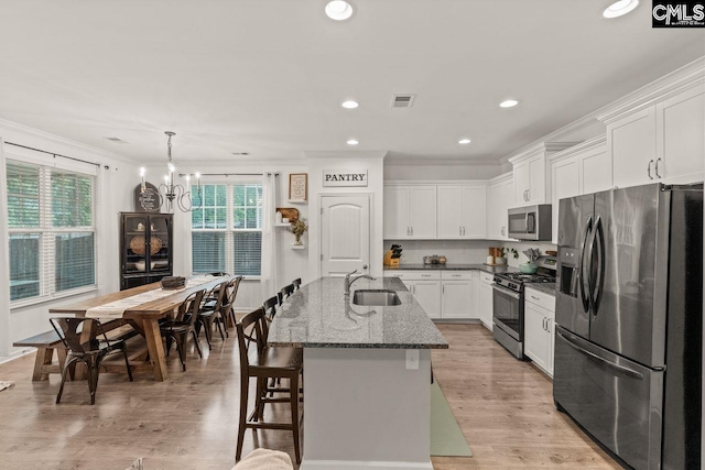 kitchen with white cabinetry, a kitchen island with sink, appliances with stainless steel finishes, and light hardwood / wood-style flooring