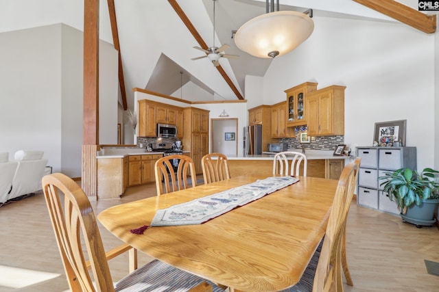 dining space with ceiling fan, light wood-type flooring, and high vaulted ceiling