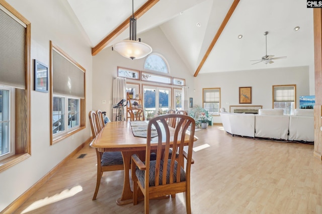 dining space with beamed ceiling, ceiling fan, light wood-type flooring, and high vaulted ceiling