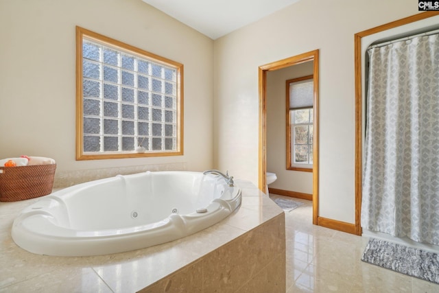 bathroom featuring tile patterned flooring, a relaxing tiled tub, and toilet