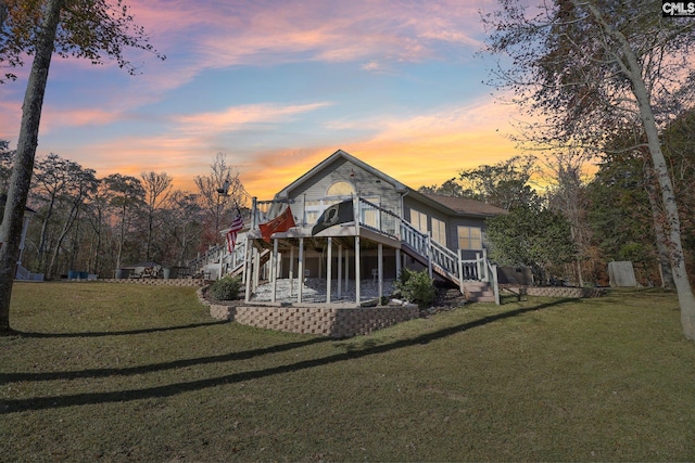 back house at dusk featuring a patio area and a yard