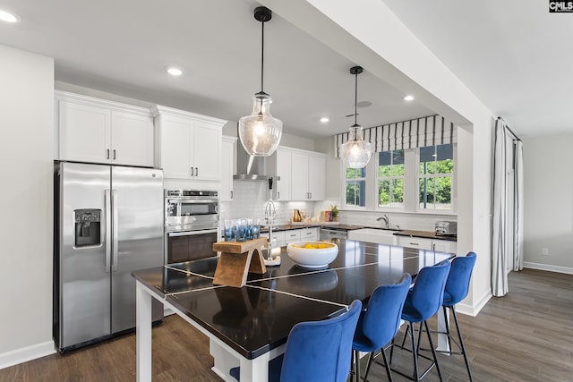 kitchen featuring dark wood-style floors, dark countertops, backsplash, appliances with stainless steel finishes, and white cabinets