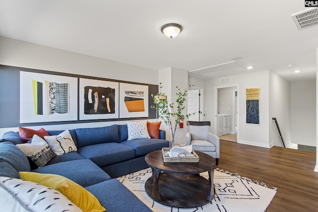 living room featuring washer / clothes dryer, visible vents, attic access, wood finished floors, and baseboards