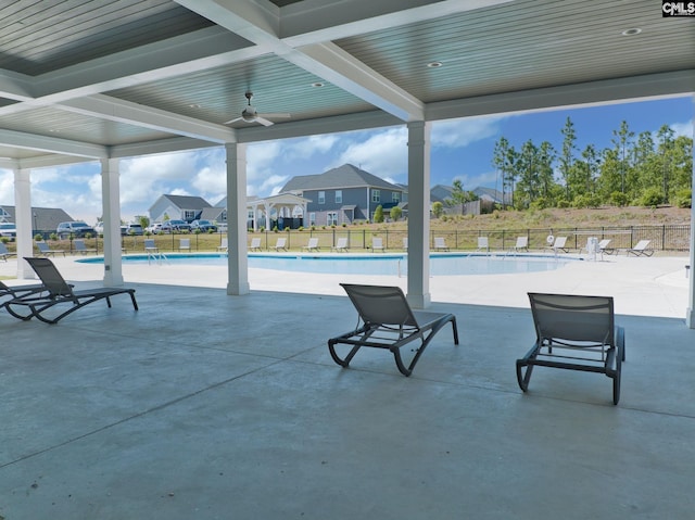 view of patio featuring a residential view, fence, a community pool, and ceiling fan