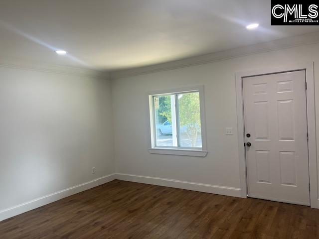 foyer entrance with ornamental molding and dark wood-type flooring