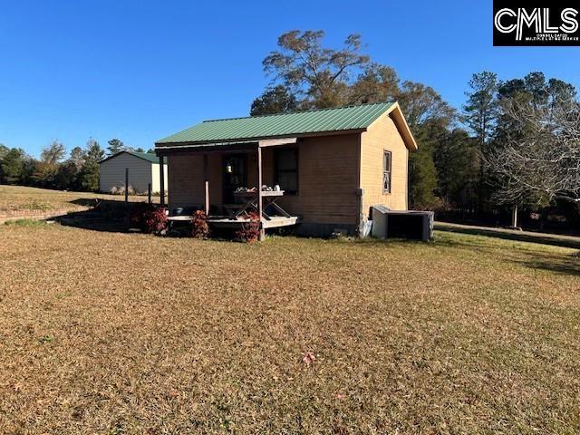 rear view of house with cooling unit and a lawn