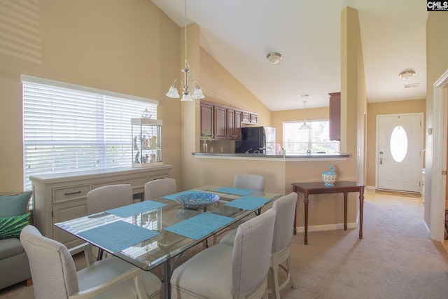 dining area featuring light carpet, a chandelier, and high vaulted ceiling