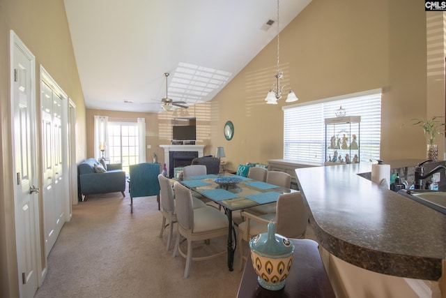 dining room featuring light carpet, ceiling fan with notable chandelier, and high vaulted ceiling