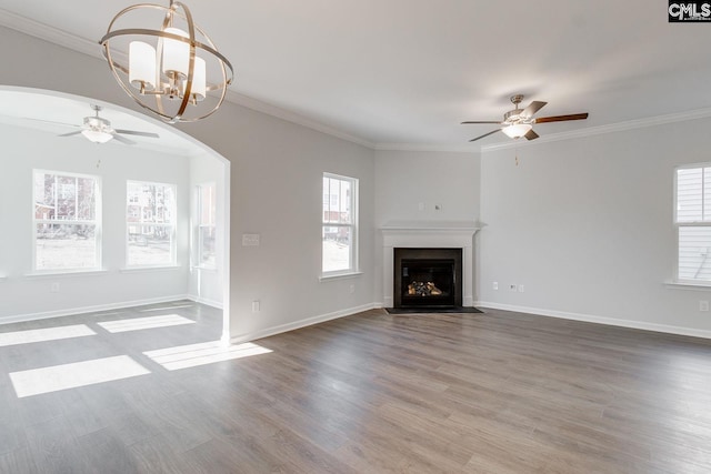 unfurnished living room featuring hardwood / wood-style flooring, plenty of natural light, crown molding, and ceiling fan with notable chandelier