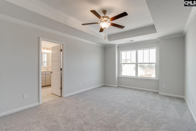 carpeted spare room with a raised ceiling, ceiling fan, and ornamental molding